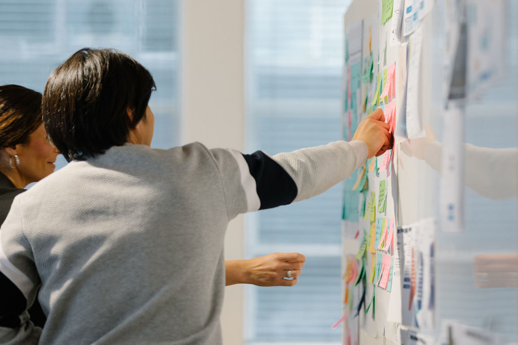 Person pointing at postit on whiteboard